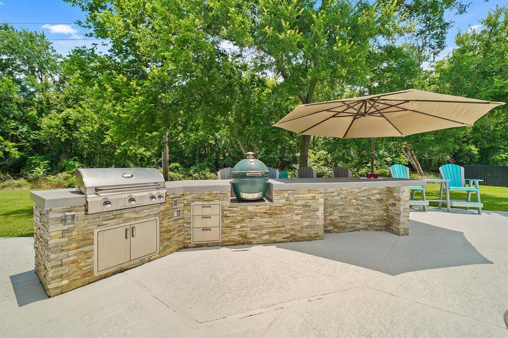 The home chef is going to love entertaining outside thanks to this custom, built-in Outdoor Kitchen! This stacked stone Kitchen includes a custom tile countertop, 4-burner gas grill, covered outlets, storage, and bar seating. The Green Egg is excluded from the sale of the home; however, it is negotiable.