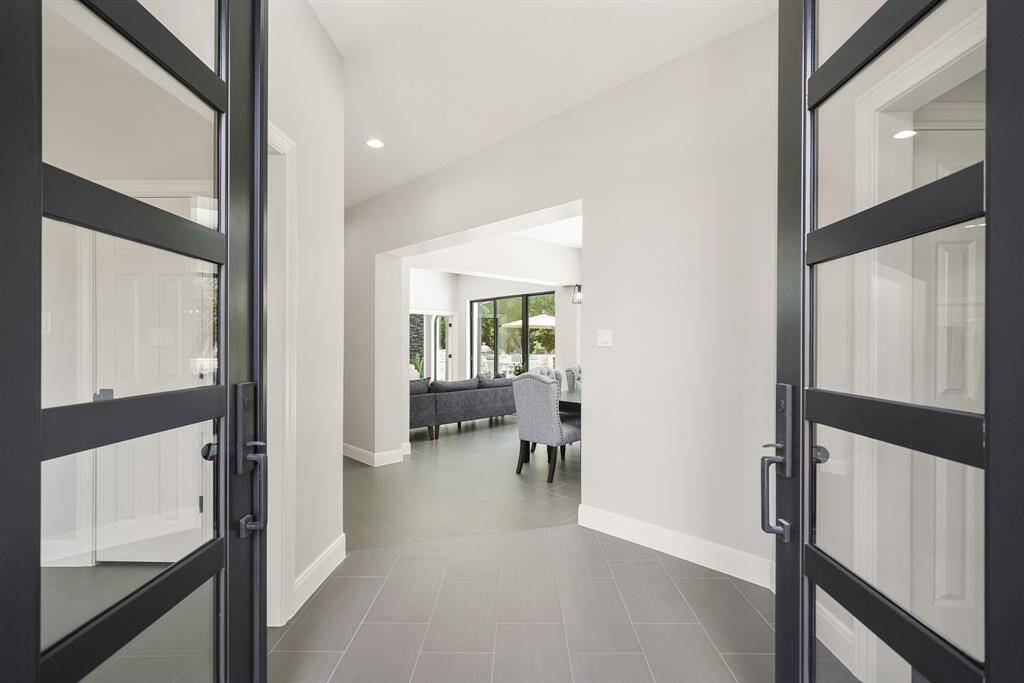 A pair of modern, glass-paned front doors welcome friends and family to this recently renovated home. Immediately upon entering the home, the eyes are drawn through the main living space and towards the wall of windows ahead.