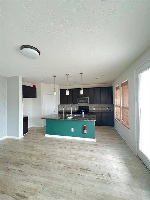 Modern kitchen with granite and dark cabinetry, and a central island with pendant lighting.