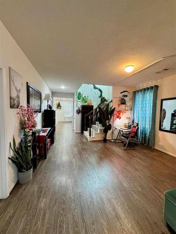 This inviting hallway features wood flooring, bright lighting, and a cozy workspace by the window.