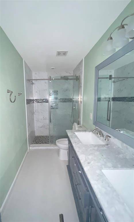Modern bathroom with a sleek design, glass-enclosed shower and a dual-sink vanity.