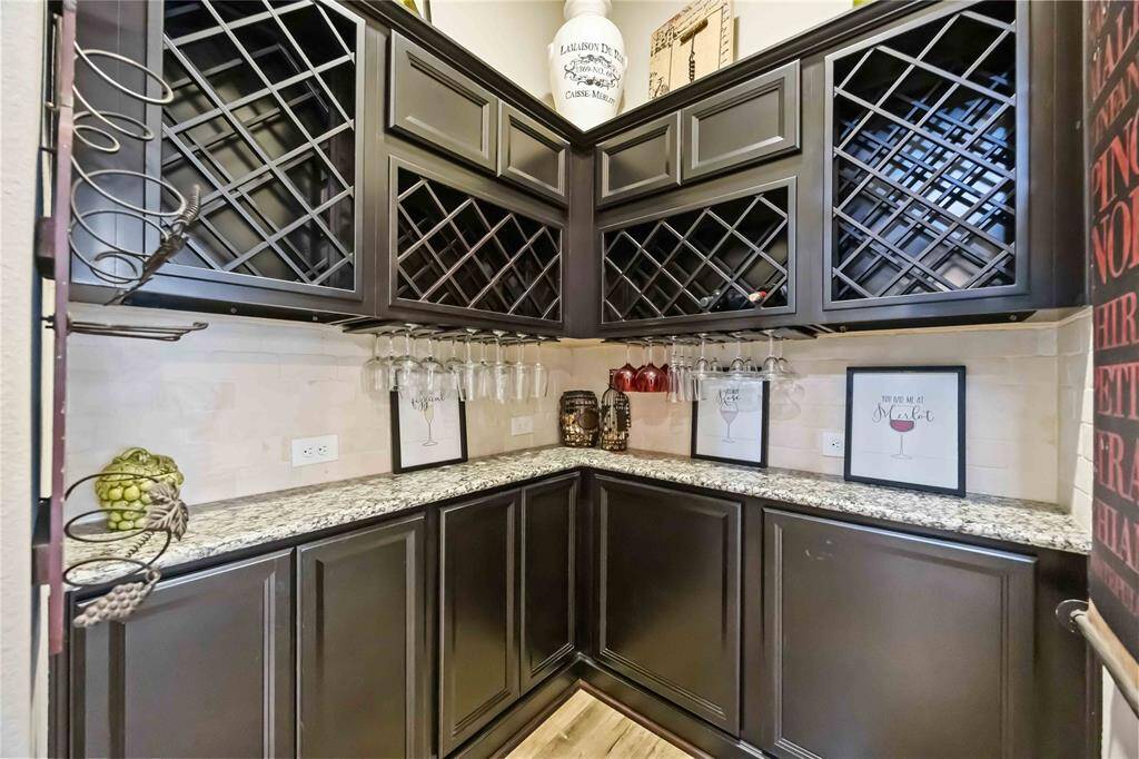 This wine cellar features a decorative iron gate, custom cabinets, and a built-in dry bar—perfect for displaying your collection and entertaining in style.