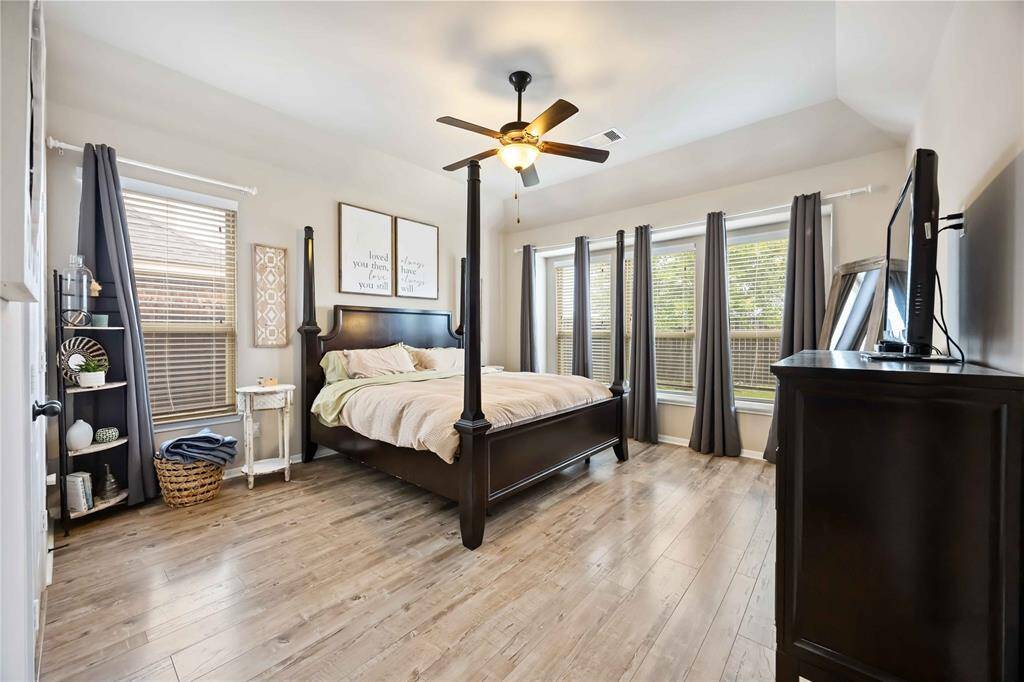 This spacious primary bedroom features a stunning four-poster bed, a wall of windows for abundant natural light, and a serene atmosphere perfect for relaxation.