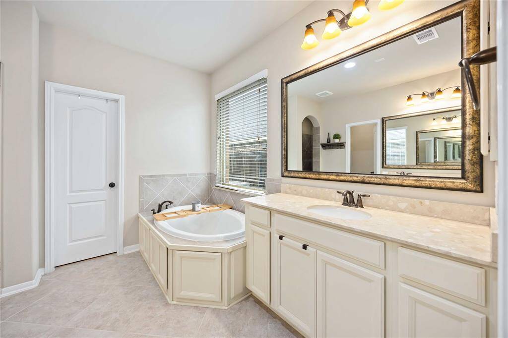 This ensuite features a sleek single-sink vanity with ample cabinets underneath.