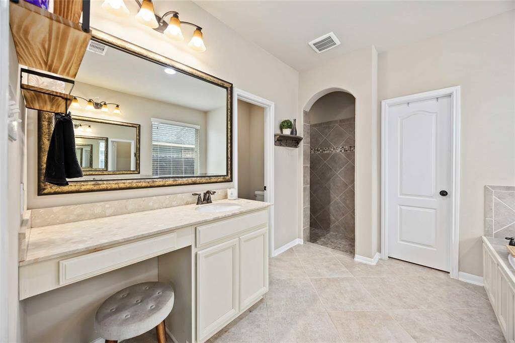 The primary bathroom boasts a vanity area with a gorgeous countertop and a walk-in shower just at the right corner,