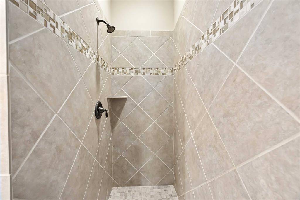 The walk-in shower showcases neutral-toned ceramic subway tiles arranged in a classic offset pattern, giving the space a timeless and clean look.