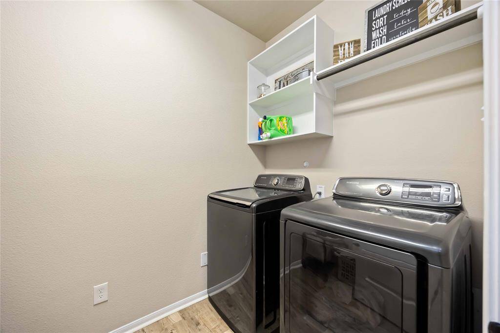 This convenient laundry space features open white built-in shelving above, offering easy access to laundry essentials.