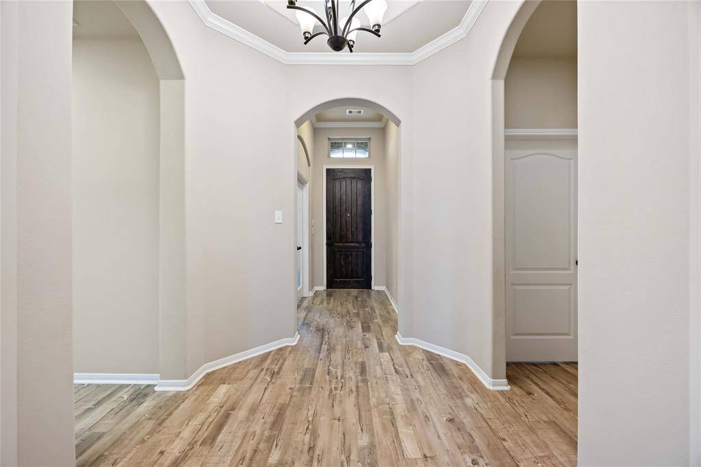 This welcoming entryway features a beautiful flooring and soaring high ceilings with crown molding adding a touch of elegance.