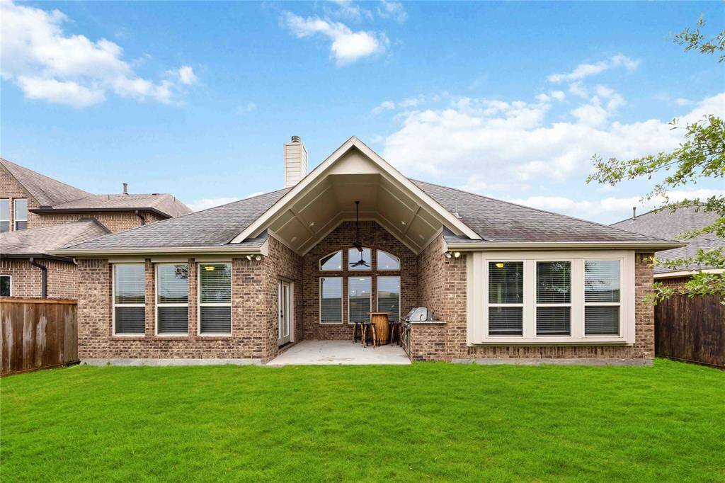 The backyard showcases a stunning full-brick exterior complemented by elegant, oversized windows.