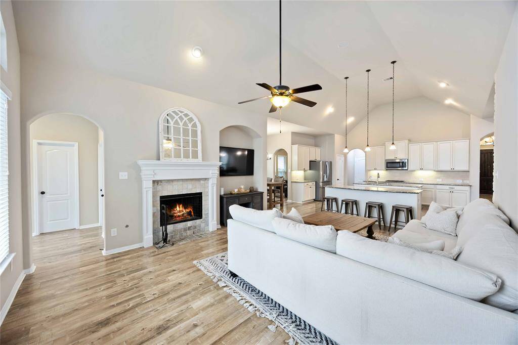 This inviting living room features a cozy fireplace and a seamless flow into the kitchen, creating the perfect space for relaxing or entertaining guests.