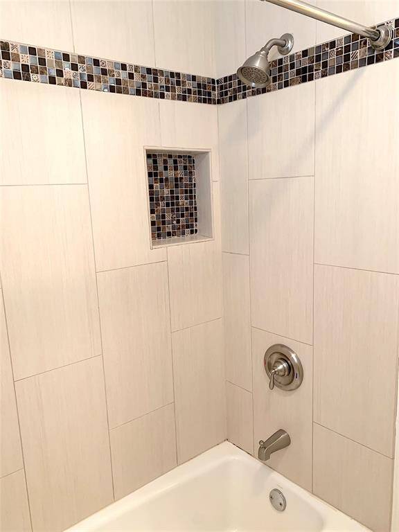 View of tub with shower head. Pretty tile work details.