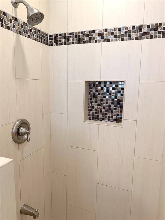 Primary bathroom shower with lovely tile accents.