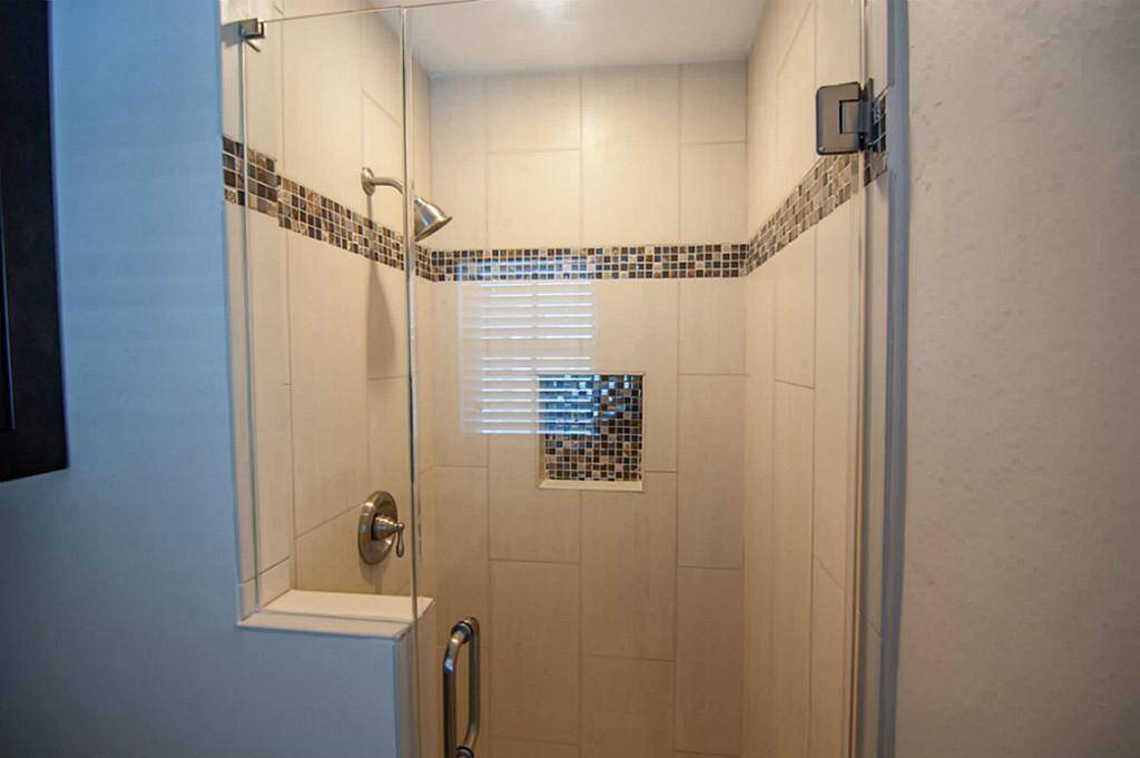 Primary bathroom shower has frameless glass shower door.