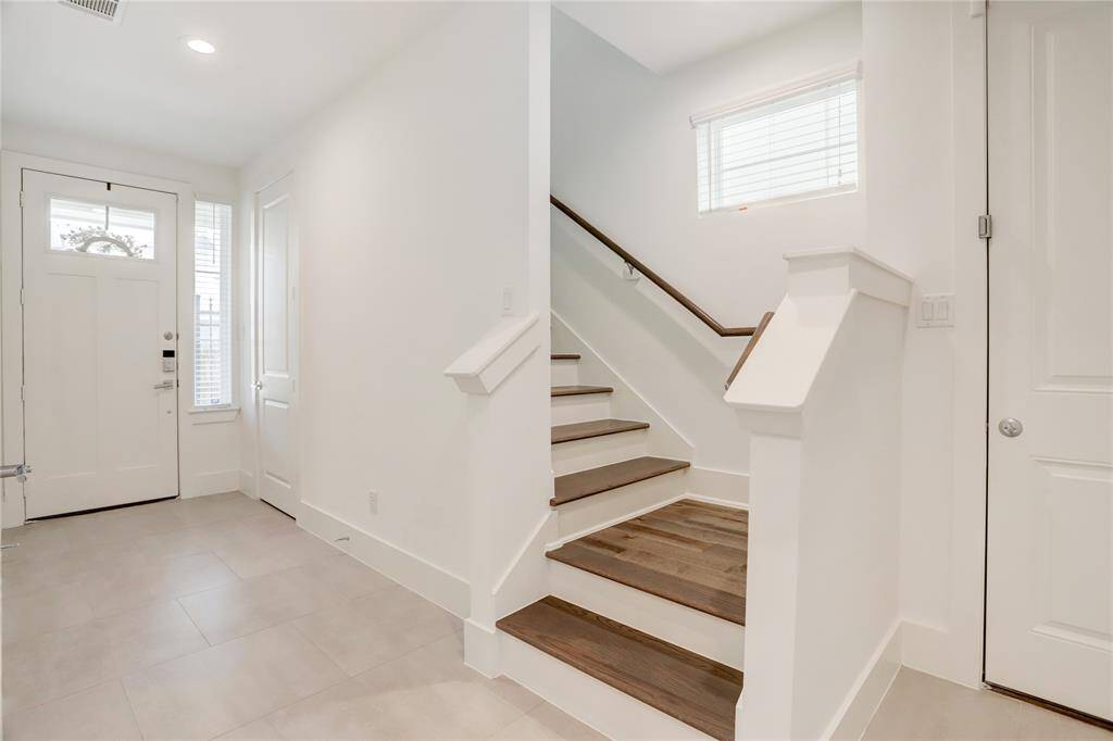The welcoming foyer area. The stairs lead to up to the main living area, and the door leads to outside. Behind this photo is the door to the downstairs secondary bedroom and ensuite bathroom.
