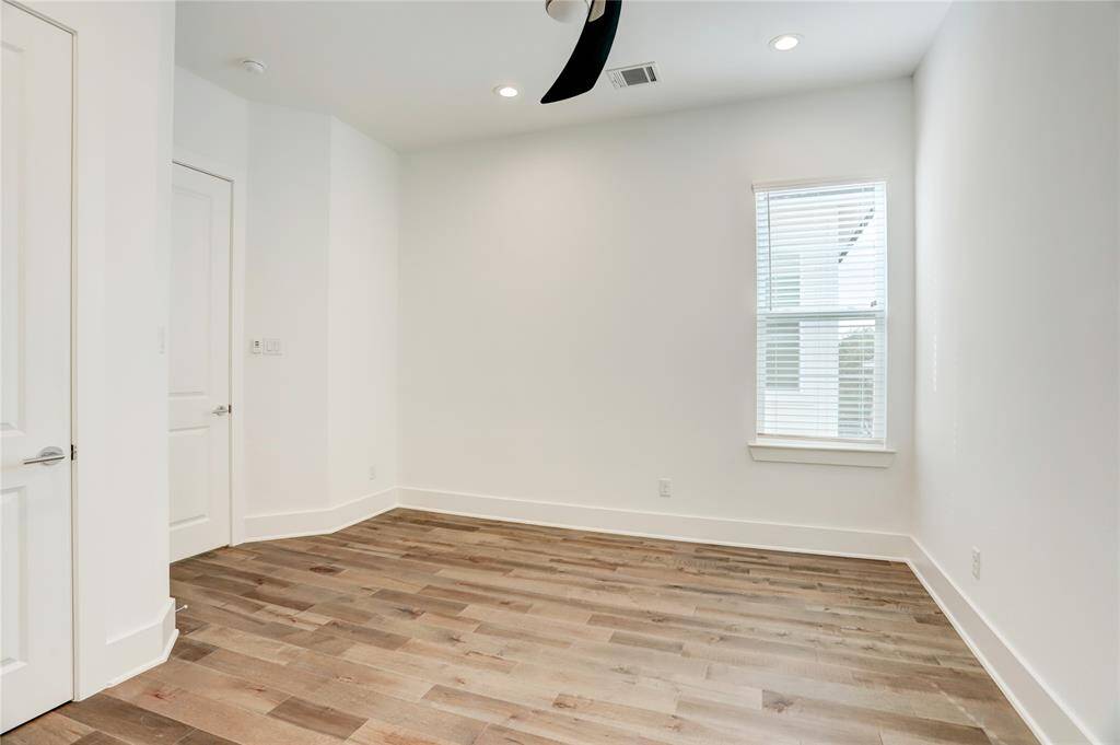 The upstairs secondary bedroom with hardwood floors, natural light, an ensuite bath, and a good-sized closet.