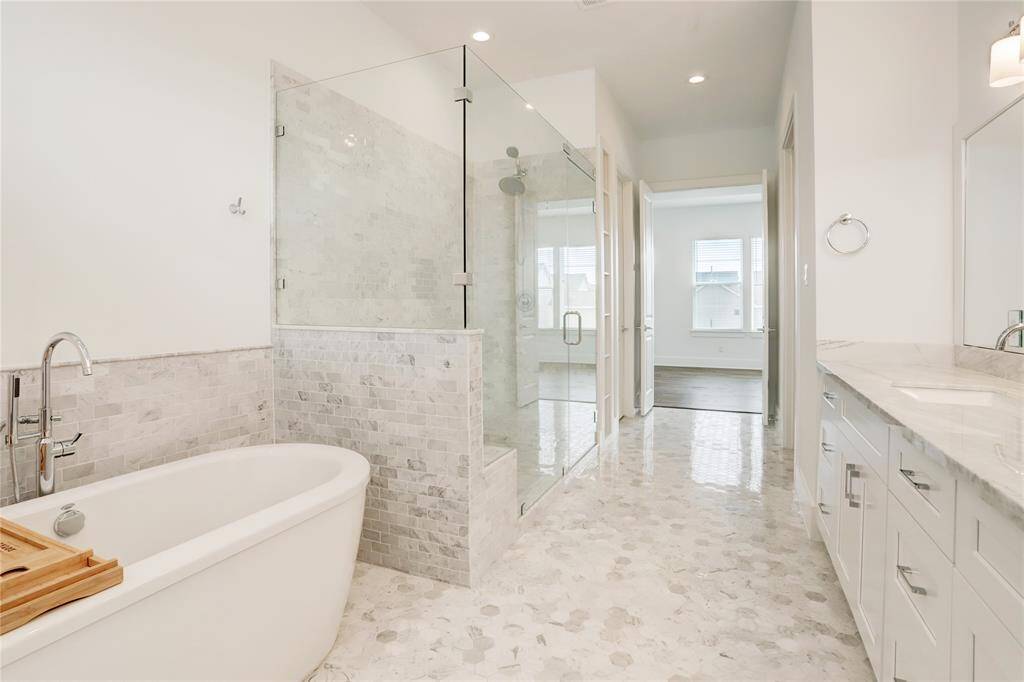 The showstopping primary bathroom, featuring a Hollywood bathtub, an enormous glass shower (with detachable showerhead and a bench), a jumbo closet, and double sinks.