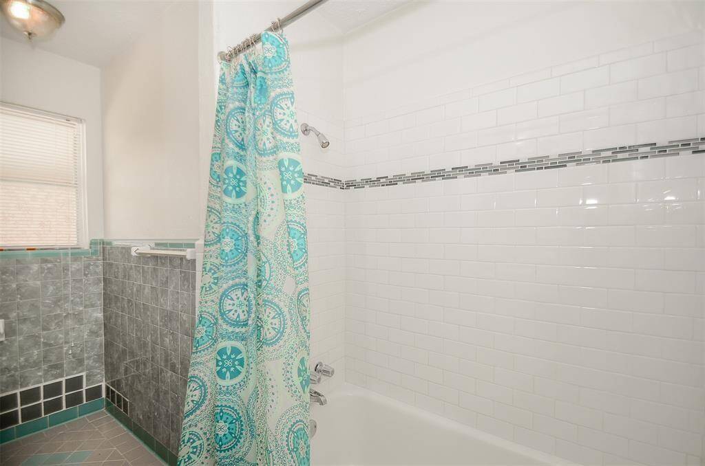 Tub in Hall bathroom with decorative tile work around tub.