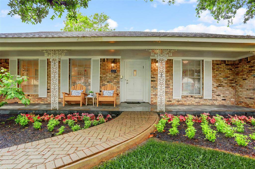 Large windows of the front porch, wrought iron columns, and tidy front landscaping