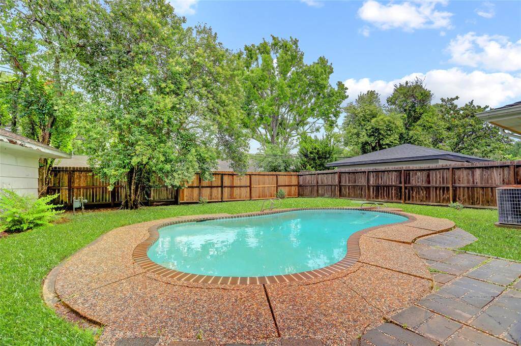 Freeform pool and fenced backyard has pea gravel decking.