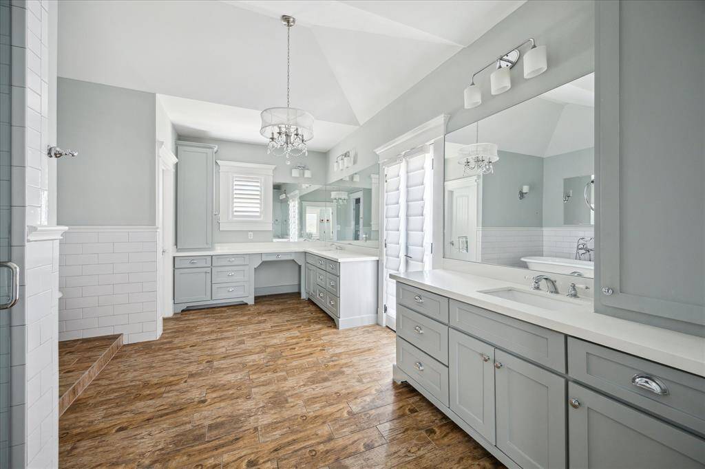 Luxury meets function in this beautifully appointed primary bathroom, featuring dual vanities, an expansive mirror wall, and abundant storage. A glass-enclosed shower and separate soaking tub provide a spa-like experience, while elegant lighting and detailed trim add a touch of sophistication. Thoughtful design ensures both comfort and convenience.