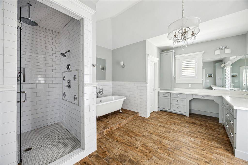 Designed for a true spa-like experience, the walk-in shower in the primary bathroom features multiple shower heads, including a soothing rain shower. Classic white subway tile extends across the walls and ceiling, while penny tile flooring adds texture underfoot. A built-in bench and niche offer comfort and convenience.