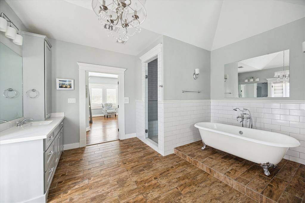 Elevated on a tiled platform, the clawfoot tub in the primary bathroom adds a timeless touch of elegance. Classic in design and complemented by polished chrome fixtures, it offers a serene space to unwind. Its placement and styling enhance the spa-like feel of the entire bath.