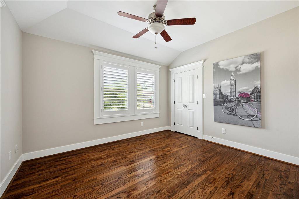 Bright and inviting, this secondary bedroom features rich hardwood floors, crisp crown molding, and a vaulted ceiling that adds architectural interest. Plantation shutters provide both light control and privacy, while a spacious closet offers practical storage. Ideal for a guest room, nursery, or home office.