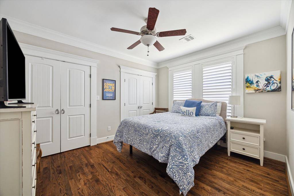 Located on the ground floor, this secondary bedroom offers a peaceful and private retreat with hardwood floors, crown molding, and ample natural light. Plantation shutters add charm and functionality, while the layout provides comfort for guests or multigenerational living. One of two downstairs bedrooms, it’s perfect for flexible use.