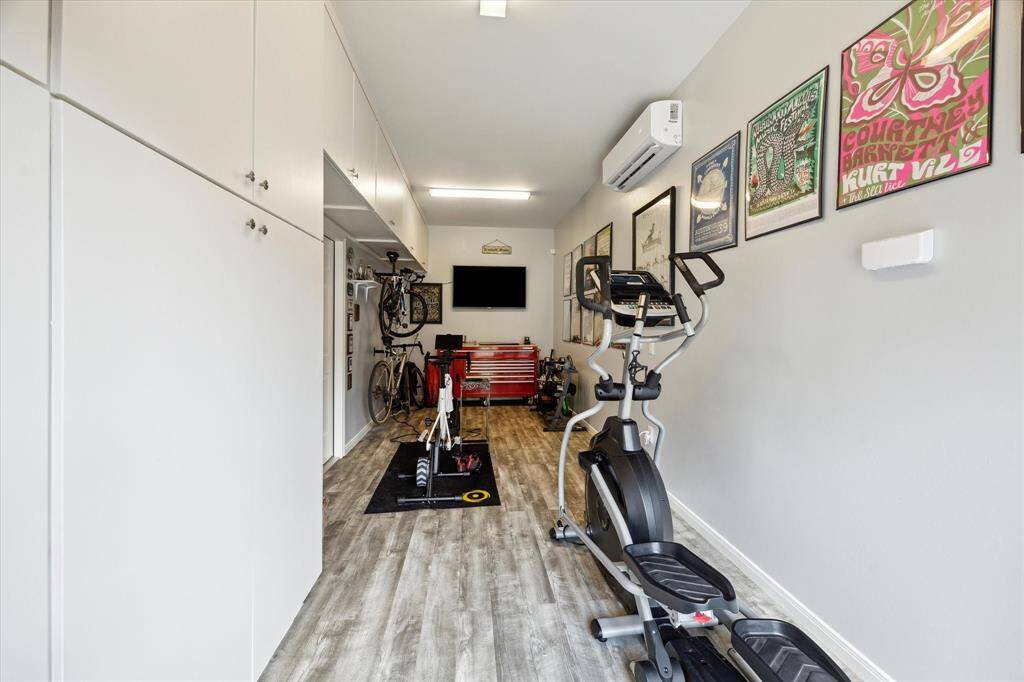 Tucked behind the oversized garage, this dedicated exercise room is a versatile bonus space equipped with built-in storage, durable flooring, and its own mini-split HVAC system. Whether used as a home gym, hobby room, or workshop, it offers comfort and flexibility just steps from the main home.