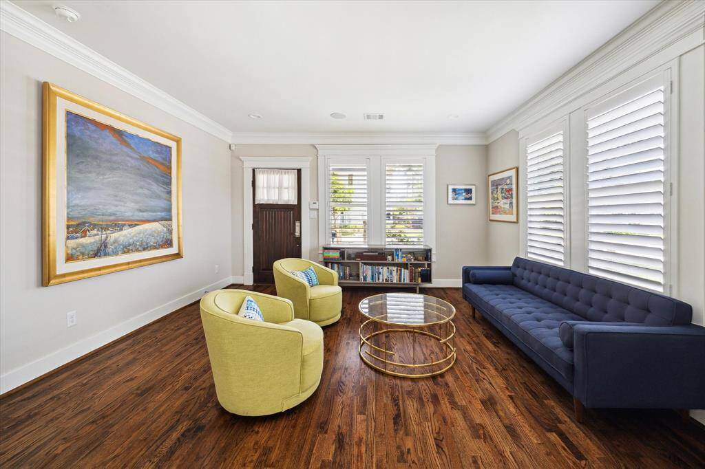 From this angle, the front living room showcases elegant crown molding, warm hardwood floors, and a gallery wall suited for a statement art piece, adding character to the space.