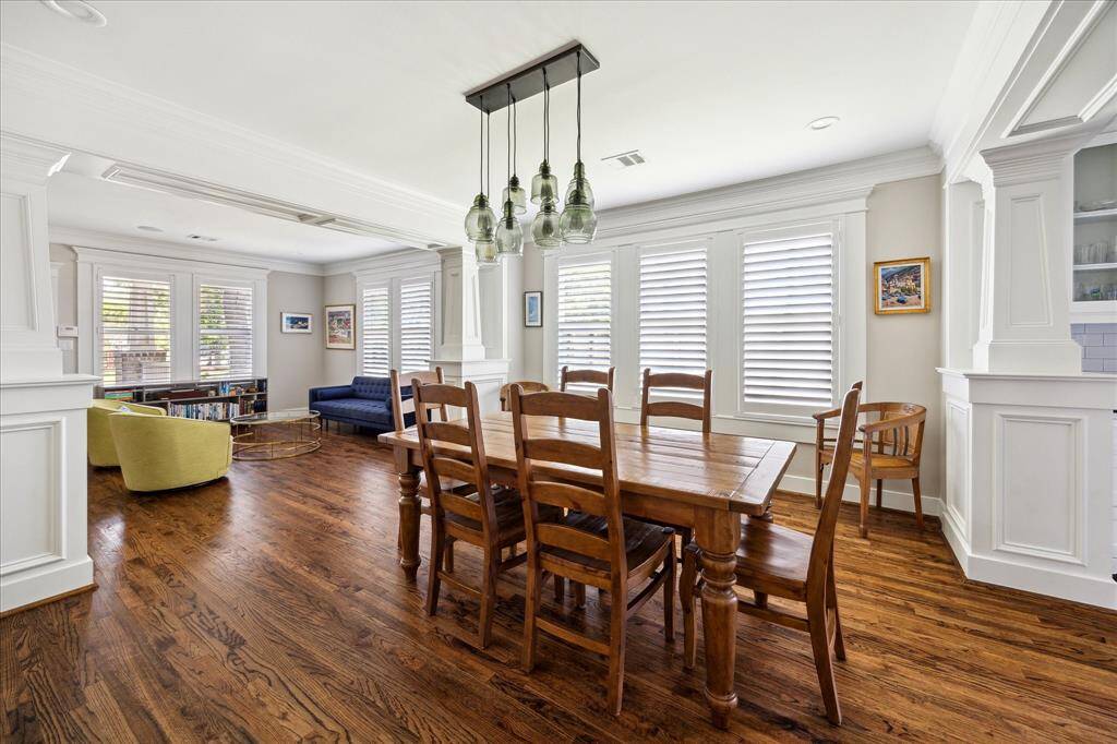 Showcasing a statement Pottery Barn light fixture, this formal dining room pairs style with sophistication. Crisp crown molding, wide plantation shutters, and rich hardwood floors create a polished yet inviting setting. The space is ideally positioned between the living area and kitchen, offering both flow and function for everyday living or entertaining.