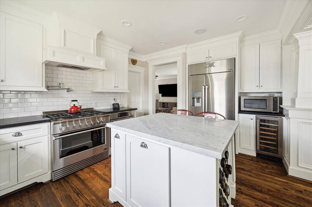 Anchoring the kitchen is a beautifully crafted island with a polished stone top that adds both style and functionality. Designed with breakfast bar seating, it’s ideal for casual dining or conversation while cooking. The island is surrounded by top-of-the-line stainless steel appliances, enhancing both the workspace and the overall flow of this thoughtfully designed kitchen.