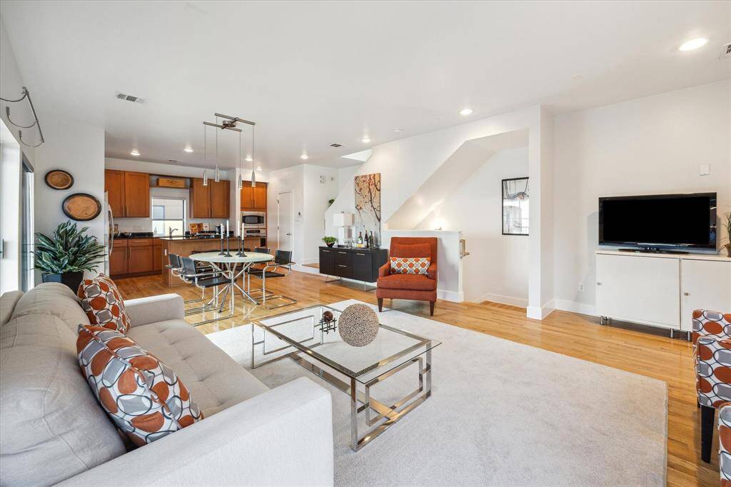 This photo showcases a modern open-concept living space. Because it is a corner, the room is bright and inviting, with plenty of natural light.
