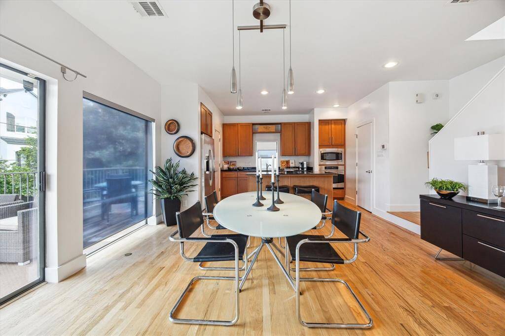 The dining area is dining area adjacent to the open kitchen and includes wonderful lighting.  The space is bright, featuring access to a balcony through sliding glass doors.