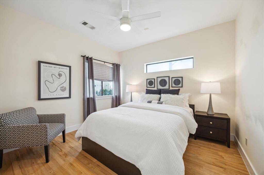 This third floor secondary bedroom features a ceiling fan and hardwood floors while natural light streams in through a window