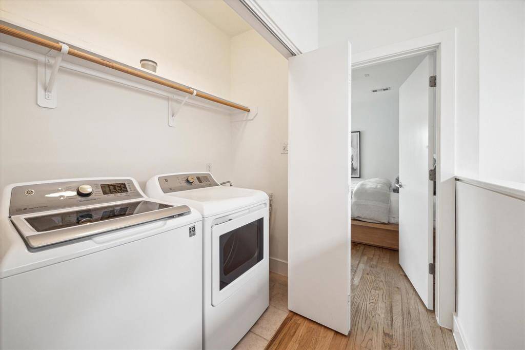 This photo shows a compact laundry area with a washer and dryer, conveniently located between the bedrooms on the third floor. It features a shelf for storage above the appliances and wood flooring.