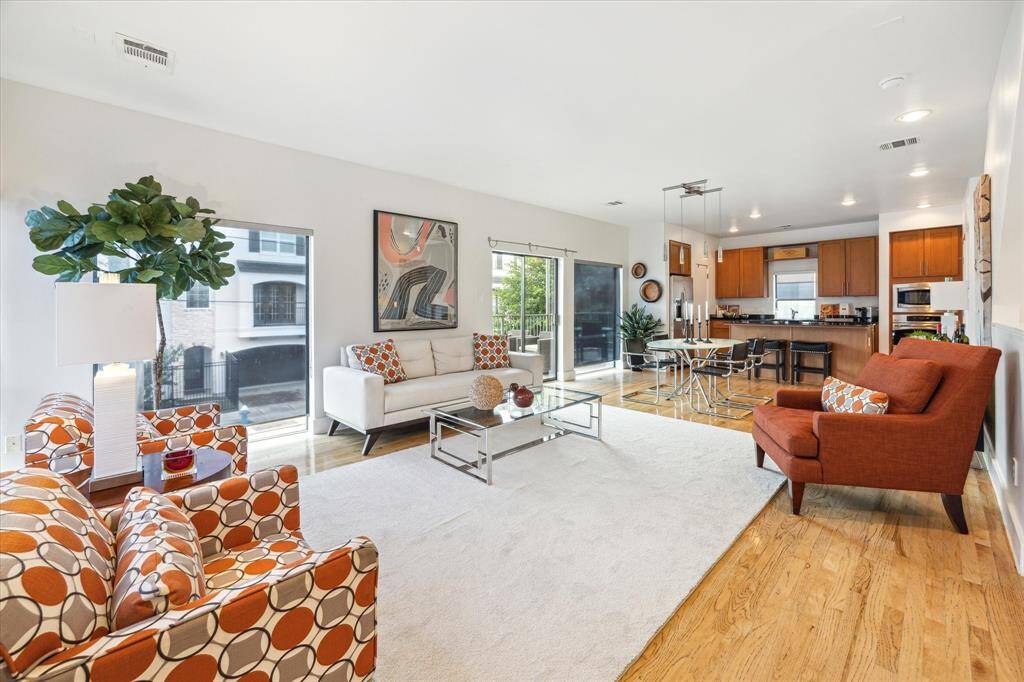 This spacious open-concept living area features hardwood floors and abundant natural light. The adjoining kitchen has sleek cabinetry and a breakfast bar, creating such an inviting and comfortable space.