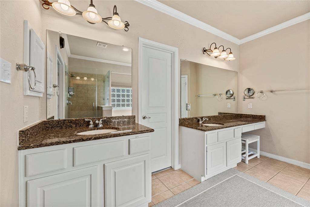 The primary bath features dual vanities, providing ample personal space along with an abundance of custom cabinetry for seamless organization.