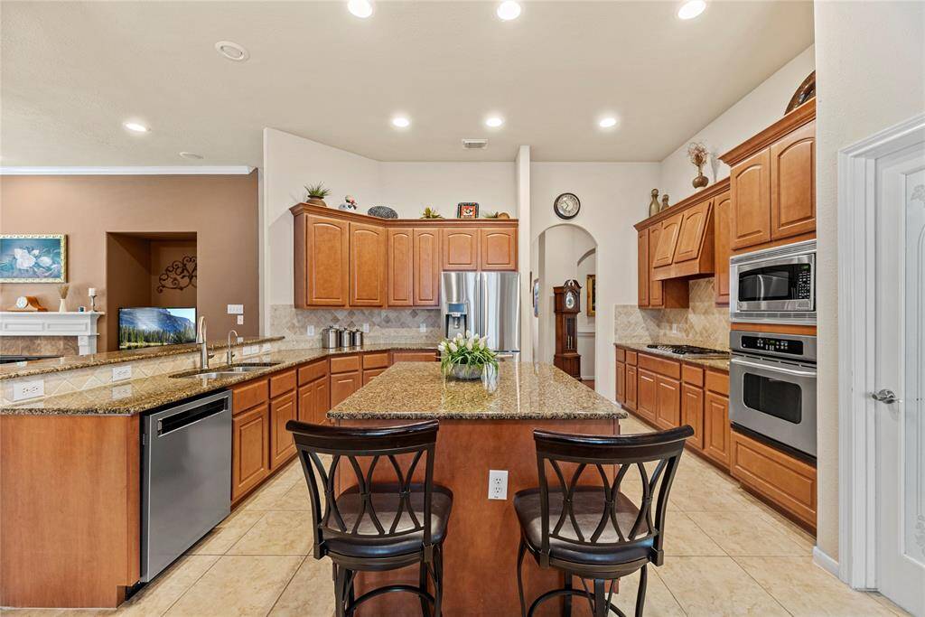 Your chef inspired kitchen awaits! Features include granite countertops paired with a coordinating stone backsplash, stainless steel appliances, rich cabinets, recessed lighting, and a sprawling island with breakfast bar seating.