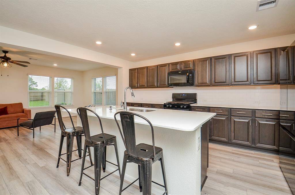 Bright, spacious Sunroom featuring large windows, modern ceiling fan, and wood like flooring. Includes a cozy seating area,  perfect for families over looking the backyard.