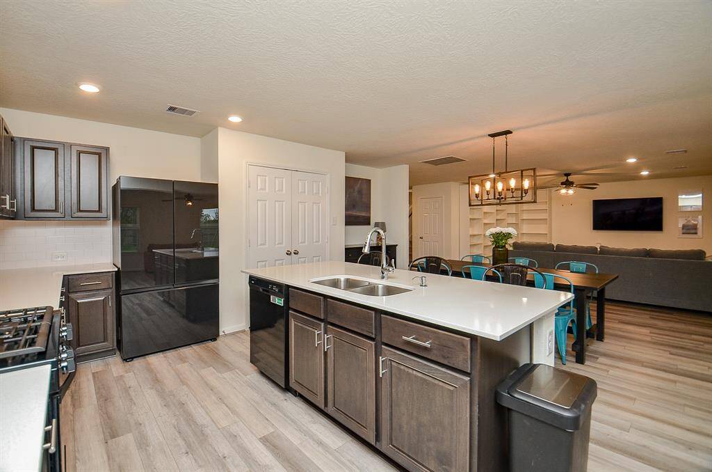 Bright and spacious sunroom with large windows overlooking a fenced backyard. Features include laminate flooring, a ceiling fan, and access to the patio through a glass door. The room is cozy with modern seating and a small play area.