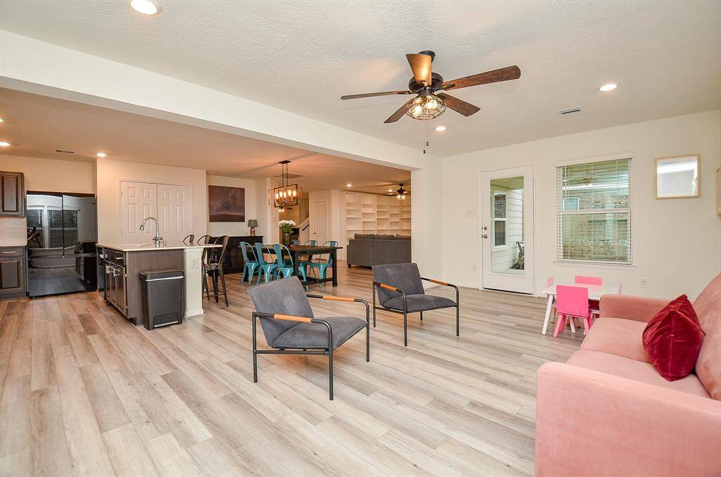 This cozy nursery features soft carpeting, a gray crib, and a comfortable rocking chair. The walls are adorned with colorful space-themed artwork, and a large window provides ample natural light.