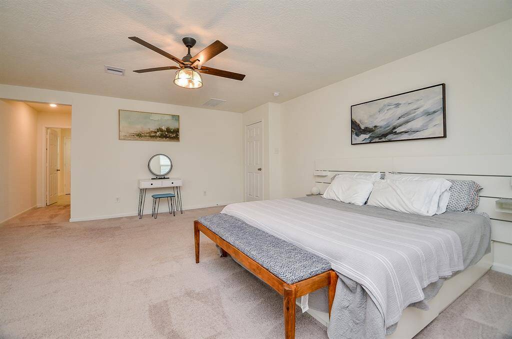 This photo shows a spacious, carpeted gameroom featuring a half wall, recessed lighting, and a small office setup, perfect for a home office or additional living space.