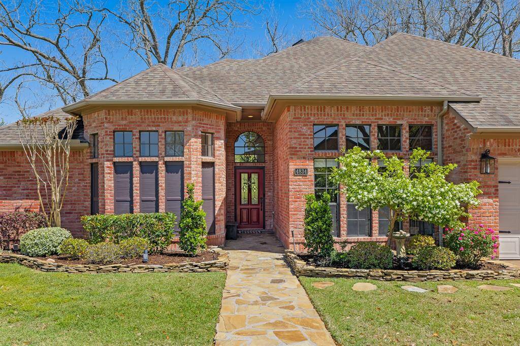 Guests will traverse the picturesque stone walkway leading to the glass-plated front door with paneled transom above. A pair of garden beds, lined with stacked stone, adds dimension and a pop of color thanks to the low maintenance trees and shrubs that frame the entryway.