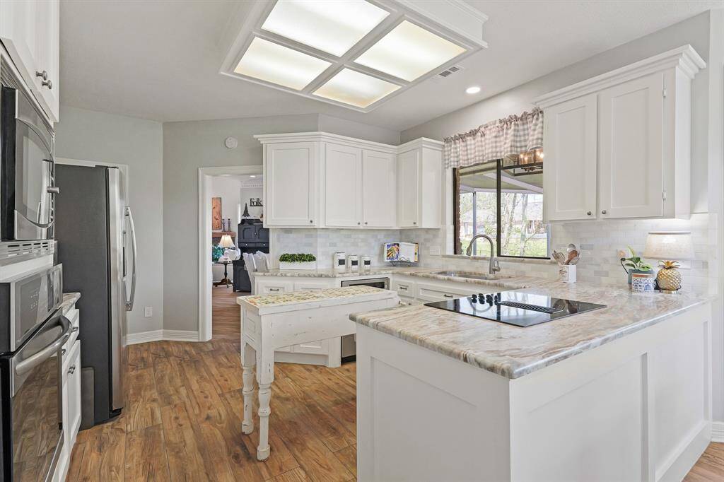 A white Kitchen is timeless! Adorned with variegated subway tile backsplash, a granite countertop with deep veining, and a statement island with tiled top, the home cook is sure to feel inspired.