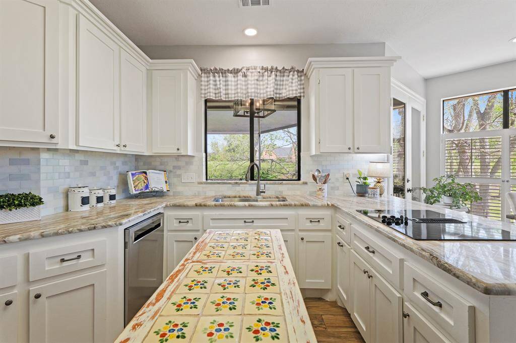 Washing dishes at this dual-basin, stainless steel sink will never feel like a chore thanks to the breathtaking Backyard views beyond. This angle also highlights the beauty of this antique island with towel hang and tile top.
