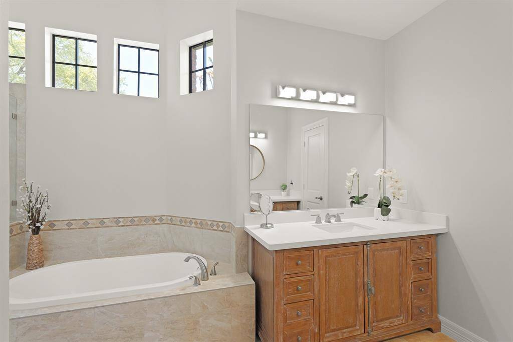 The Primary Bath boasts old world charm thanks to the furniture-like vanities adorned with brushed nickel hardware. Both vanities are topped in white quartz and contain and undermount sink.