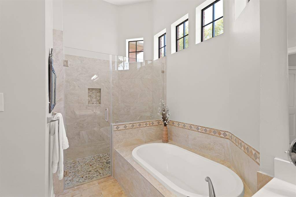Soak away the stress of the day in this spacious soaker tub framed in coordinating ceramic tile. Five transom windows above allow natural light to fill the space without compromising on privacy.