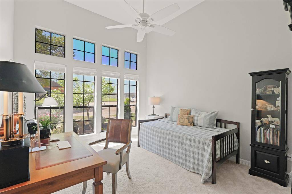 This Secondary Bedroom boasts tall ceilings, wall-to-wall plush carpeting, walk-in closet, and quartet of windows with transoms above overlooking the Front Yard.