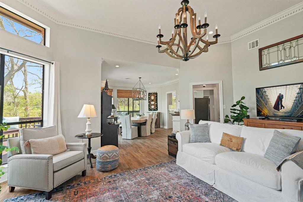The Living Room boasts tall ceilings, LVP flooring, intricate crown molding, and a high-end chandelier. The main living space operates as separate rooms but keeps an exposed line of sight throughout the entirety of the space, providing an open and inviting feel.